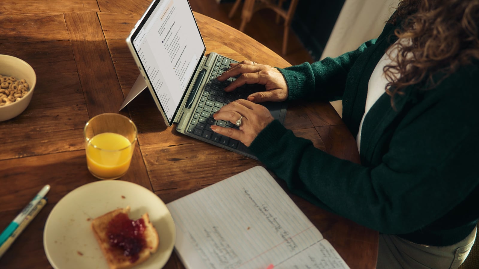 Woman typing on a laptop at a wooden table set with breakfast items, representing focused investment research and company analysis.