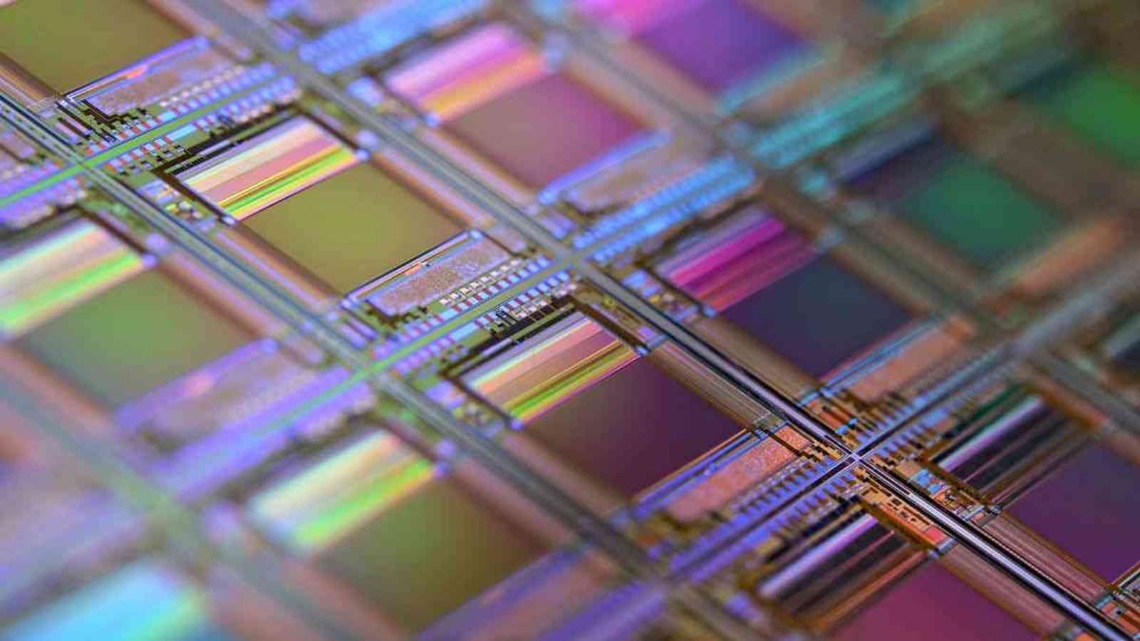 Macro photograph of a silicon wafer showing the grid of individual semiconductor dies with rainbow diffraction